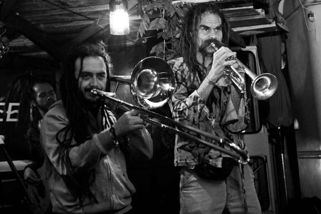 photo noir et blanc de deux personnes entrain de jouer de la musique avec une trompette et un trombone